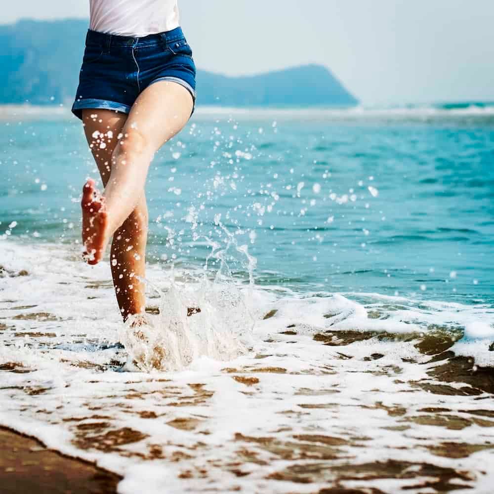 woman kicking water at beach